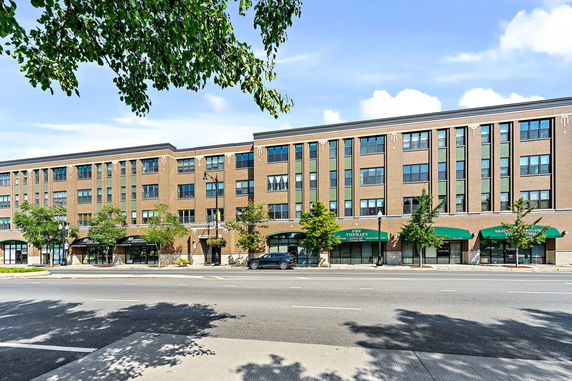 Front view of a multi-story brick building with shops on the ground floor.