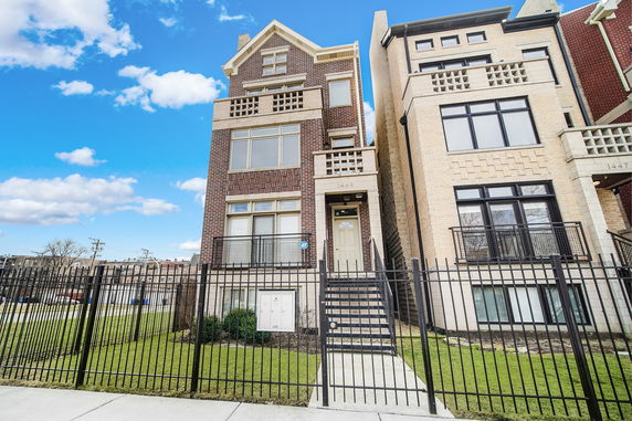 Front view of a multi-story brick house with a staircase leading to the entrance.