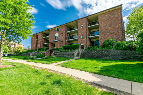 Front view of a multi-story brick building with balconies and landscaped surroundings.
