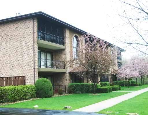 Front view of a two-story brick building with balconies and arched windows.
