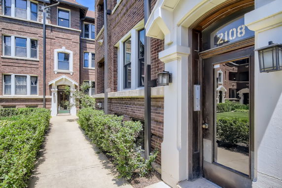 Entrance of a brick apartment building with a reflective glass door.
