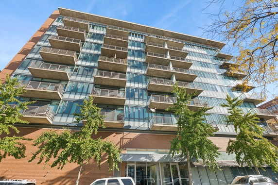 Front view of a multi-story apartment building with balconies and large windows.