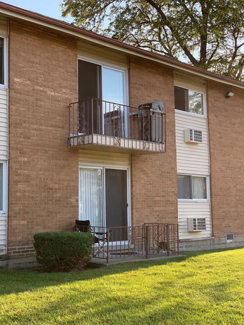 Front view of a multi-story brick building with balconies and sliding doors.