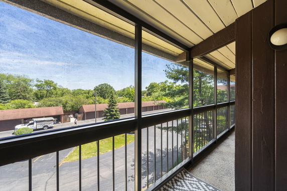 View from a balcony overlooking an outdoor parking area and surrounding greenery.