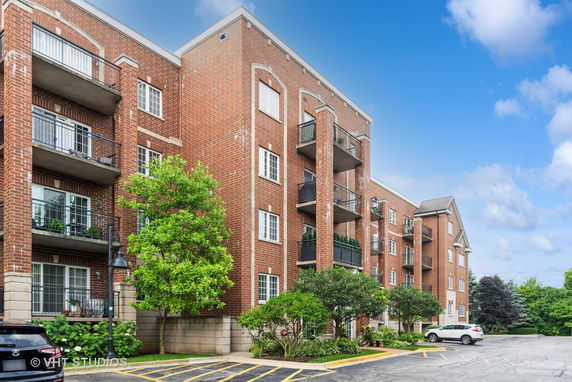 Front view of a multi-story brick apartment building with balconies.