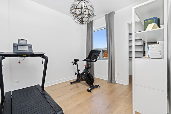 Room with exercise equipment including a treadmill and stationary bike.