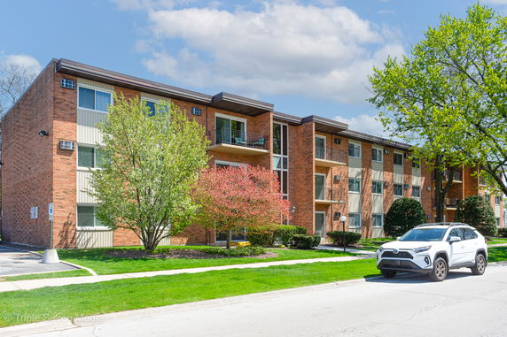 Front view of a three-story brick apartment building with balconies.