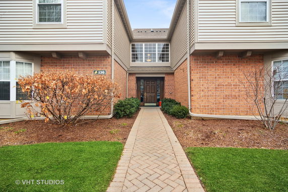 Front view of a brick building entrance with a walkway leading to the door.