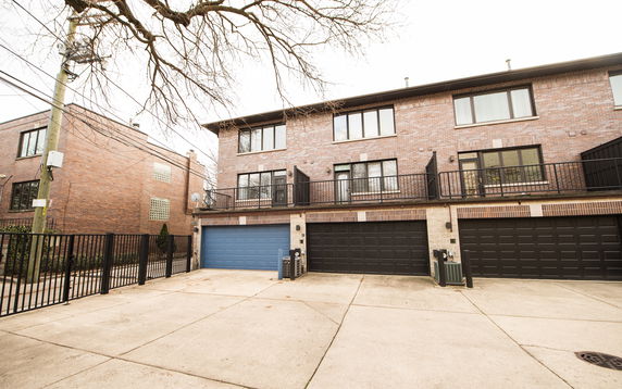 Front view of a multi-story house with multiple garages and balconies.