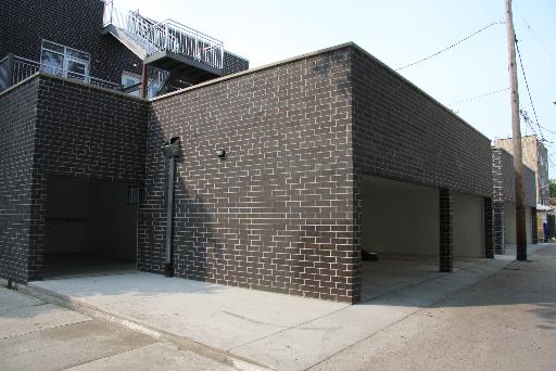 Outdoor parking with garage spaces in a brick building.
