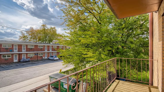View from a building's balcony showing a brick apartment complex and a parking area.