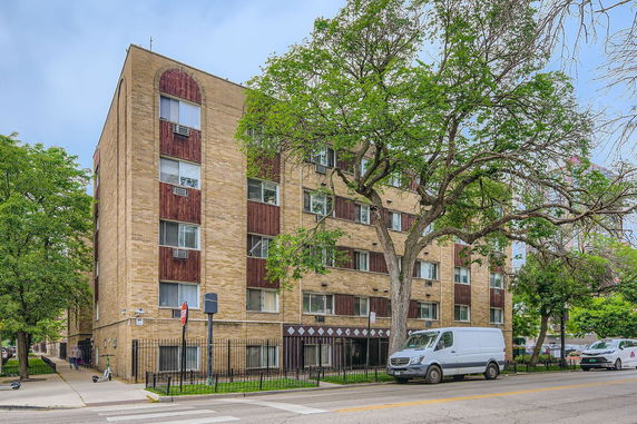 Front view of a multi-story brick apartment building with large windows.