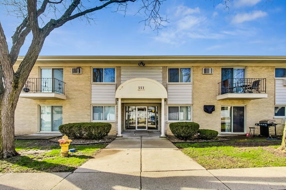 Front view of a two-story residential building with a central entrance and small balconies.