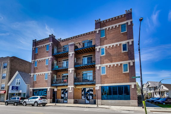 Front view of a multi-story brick building with balconies and large windows.