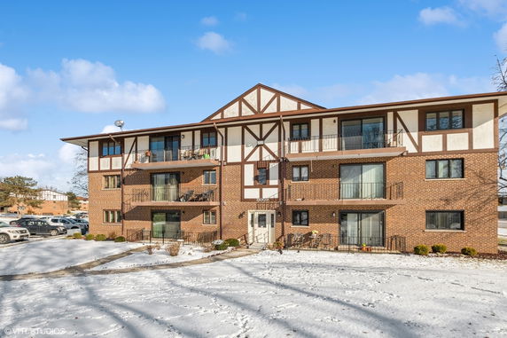 Front view of a multi-story residential building with brick facade and balconies.