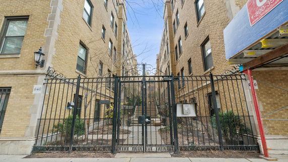 Front view of a multi-story brick building with a gated entrance.