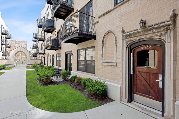 Front view of a multi-story building with balconies and a decorative archway.