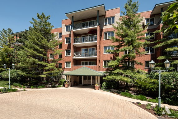 Front view of a multi-story brick apartment building with balconies and a covered entrance.