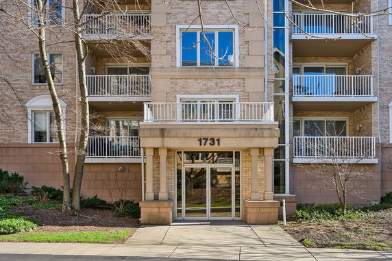 Front view of a multi-story building with balconies and glass entrance.