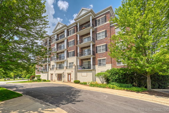Front view of a four-story brick apartment building with balconies.