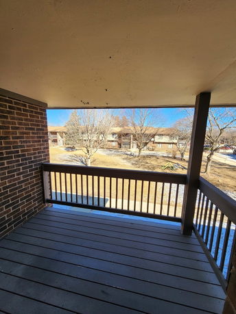 View from a covered balcony overlooking a grassy area and adjacent buildings.