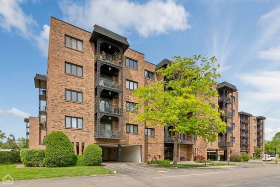 Front view of a multi-story brick residential building with balconies.