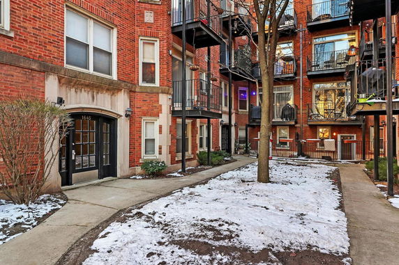 Front view of a multi-story brick apartment building with balconies.