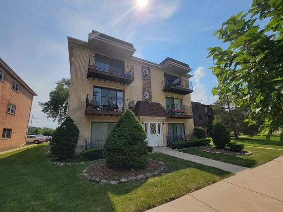 Front view of a three-story residential building with balconies.