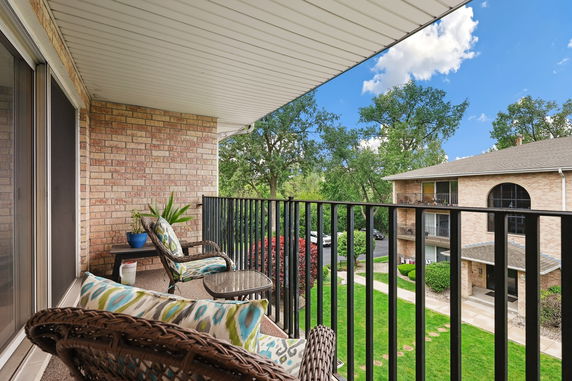 View from a balcony overlooking a grassy area and nearby buildings.