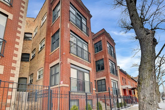 Front view of a multi-story brick residential building with balconies.