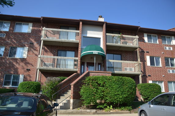 Front view of a three-story brick apartment building with balconies.