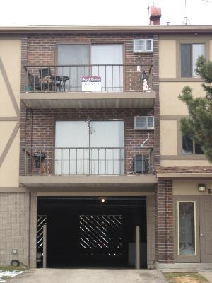 Front view of a multi-story building with balconies and a garage.