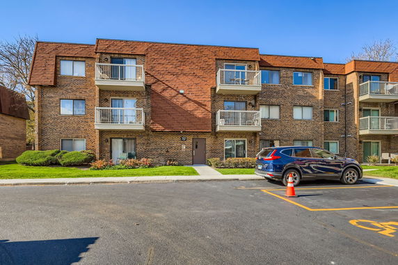 Front view of a multi-story brick apartment building with balconies.