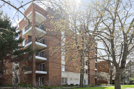 Front view of a multi-story brick apartment building with balconies.