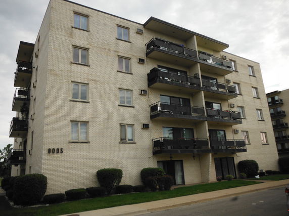 Front view of a multi-story apartment building with balconies.