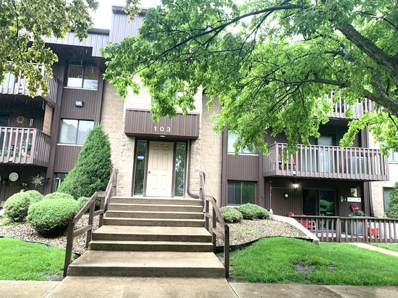 Front view of a multi-story residential building with balconies and a central entrance.