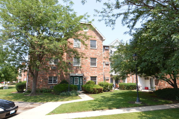 Front view of a multi-story brick building with multiple windows and a green entrance door.