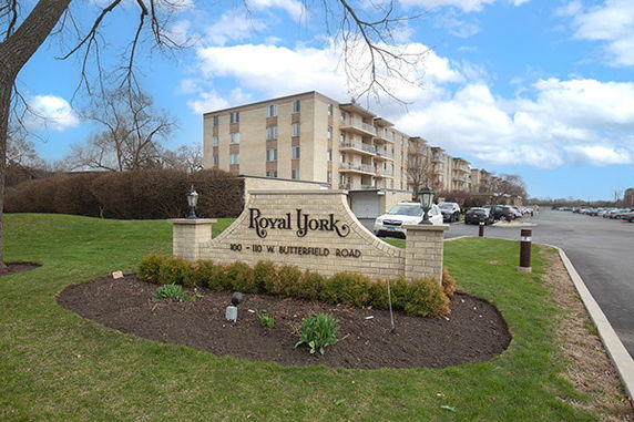 Front view of multi-story residential building with parking area.