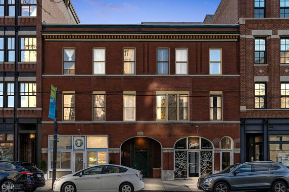 Front view of a three-story brick building with arched entrances.