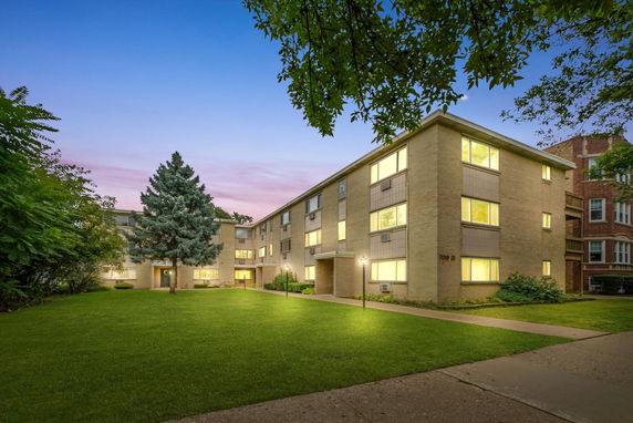 Front view of a multi-story apartment building with large windows and a central entrance.