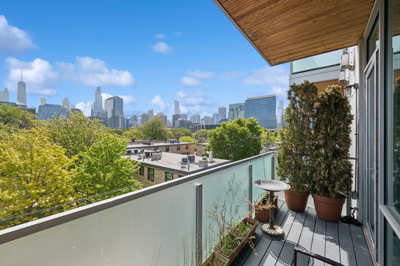 City skyline view from a balcony with glass railing and potted plants.