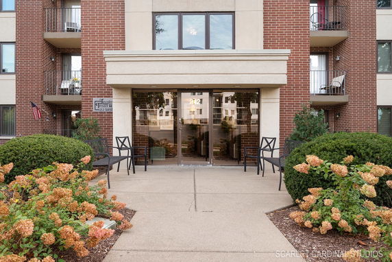 Front view of a brick apartment building with balconies and a glass entrance.