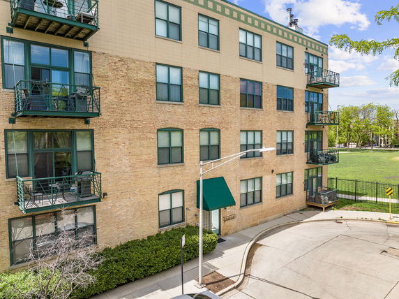 Front view of a multi-story brick apartment building with balconies.