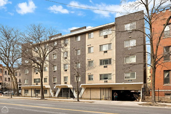 Front view of a mid-rise apartment building with a mix of dark and light brick facade.