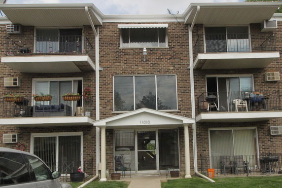 Front view of a multi-story brick apartment building with balconies.