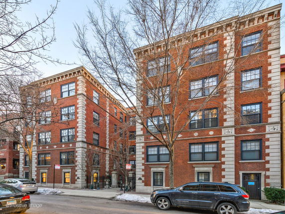 Front view of a multi-story brick apartment building with decorative trim.