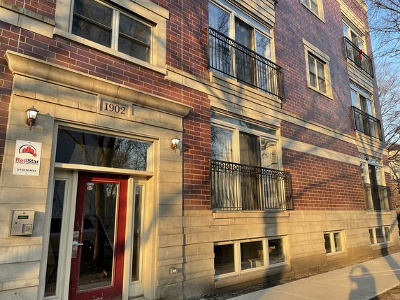 Front view of a multi-story brick building with multiple windows and balconies.