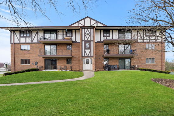 Front view of a multi-story brick apartment building with balconies.