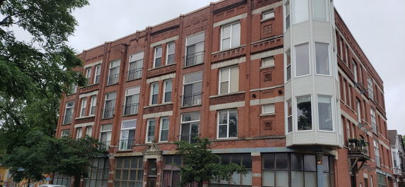 Front view of a multi-story brick building with multiple windows.