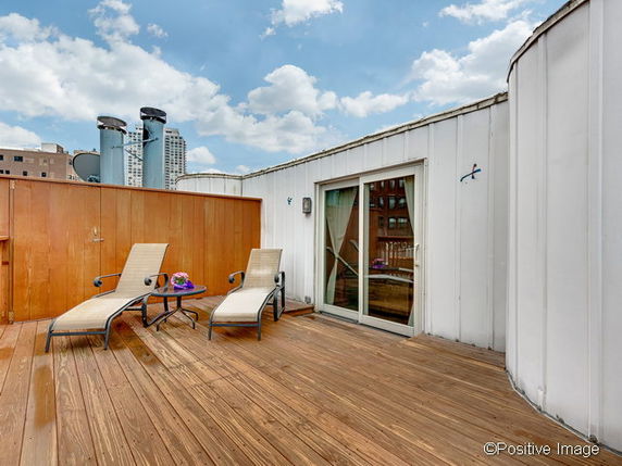 Rooftop area with wooden deck and lounge chairs.